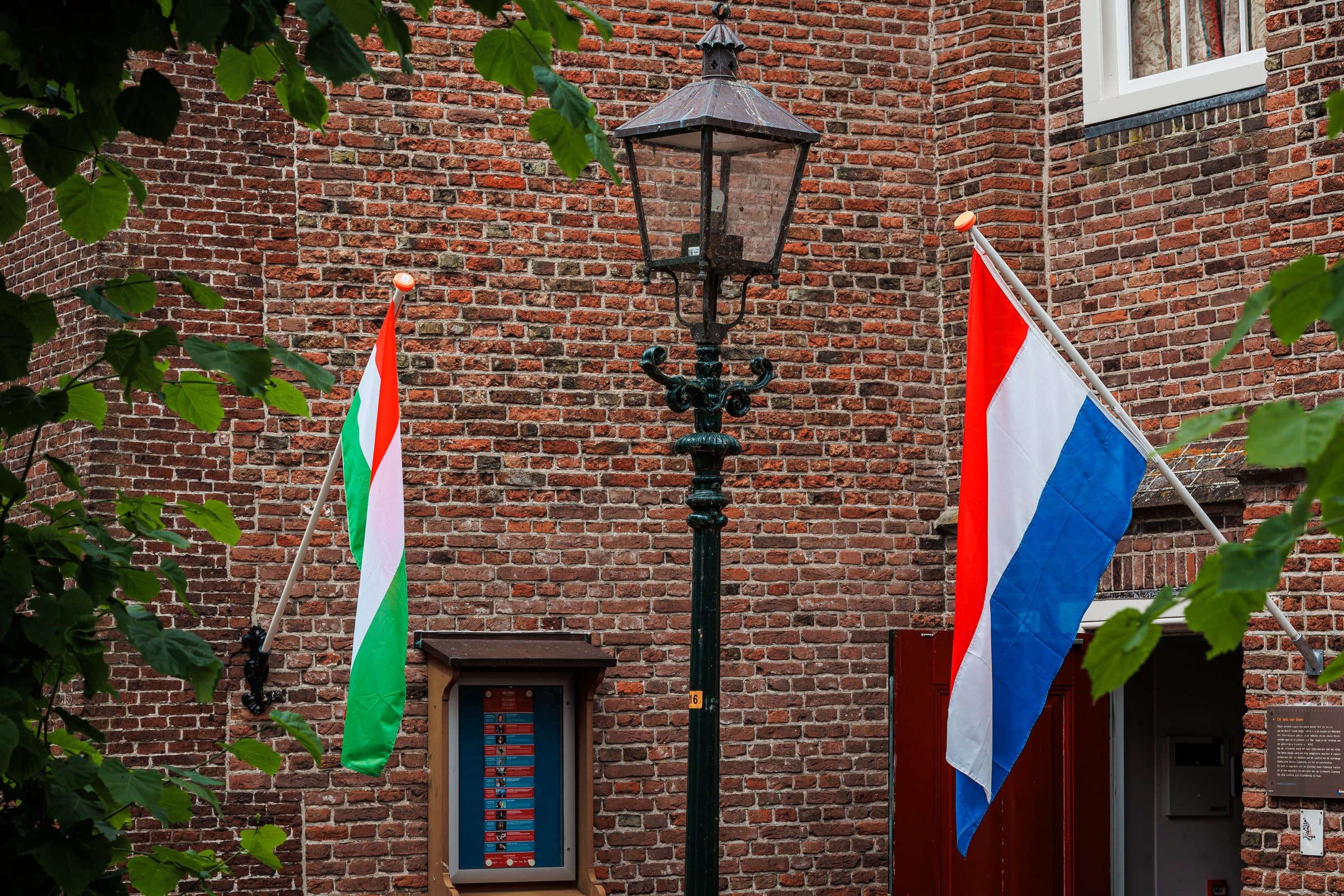 De Iraanse en de Nederlandse vlag naast elkaar aan een oude bakstenen gevel